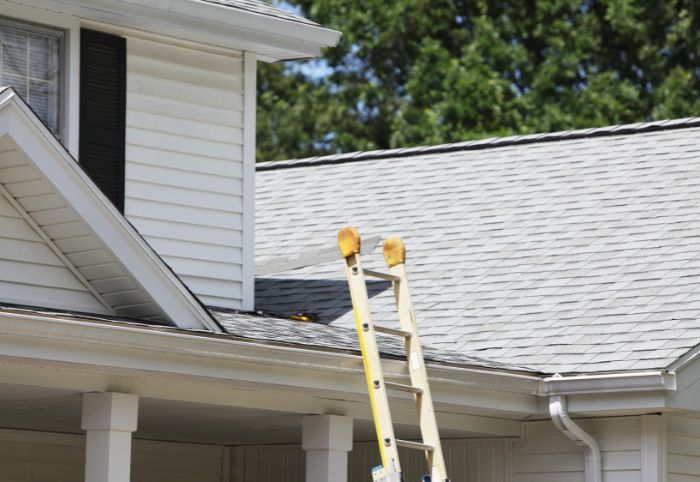 Ladder resting against house to clean gutters