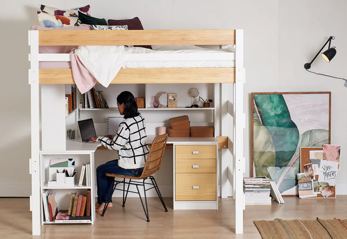 Girl sitting at a desk underneath a raised bed.