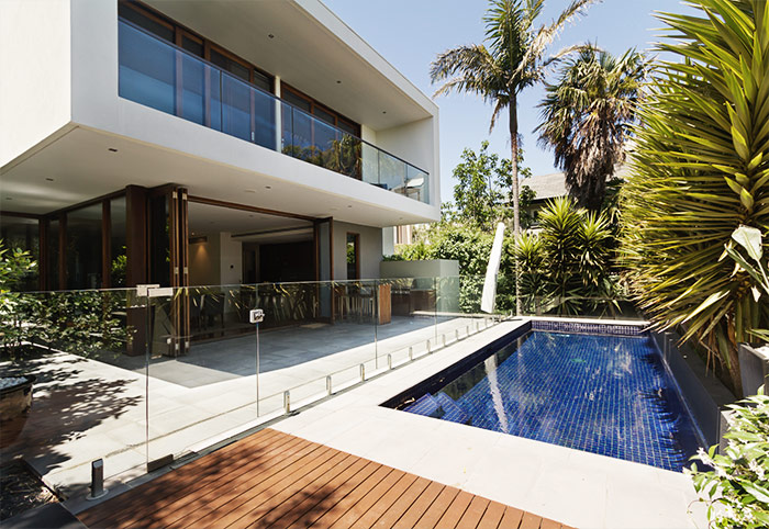 swimming pool with glass fence and palm trees