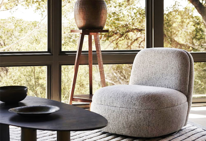 Grey accent chair in a lounge room next to a large window.