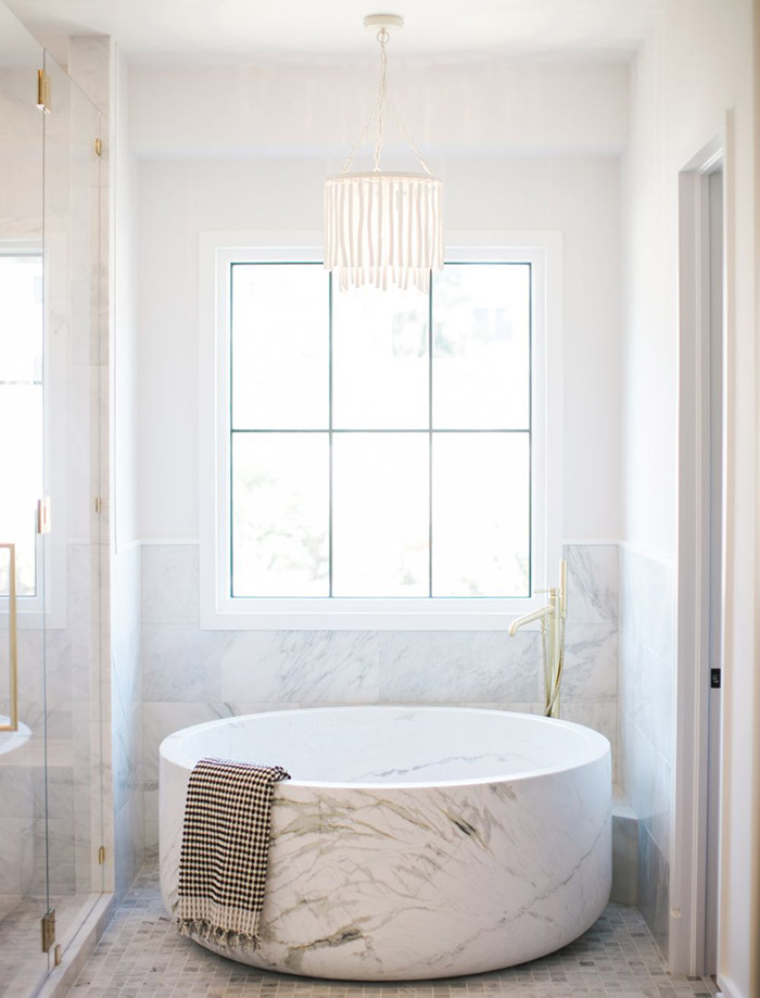 White bathtub positioned under a window in a narrow bathroom.