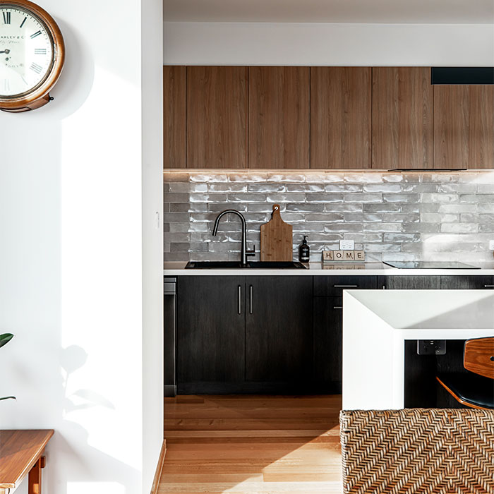 Modern kitchen with black cabinets and grey subway tiles.