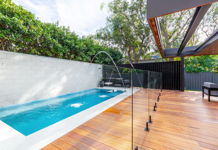 Backyard magnesium swimming pool with timber deck and fountain.