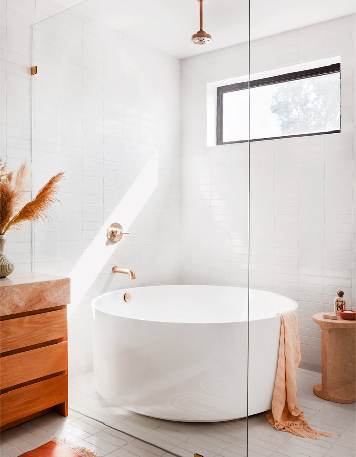 A bath tub positioned behind a glass shower screen.