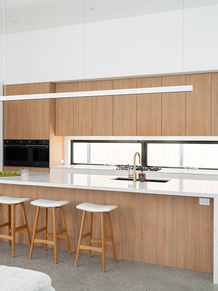 Bennett House kitchen with white bench and woodgrain cabinets.