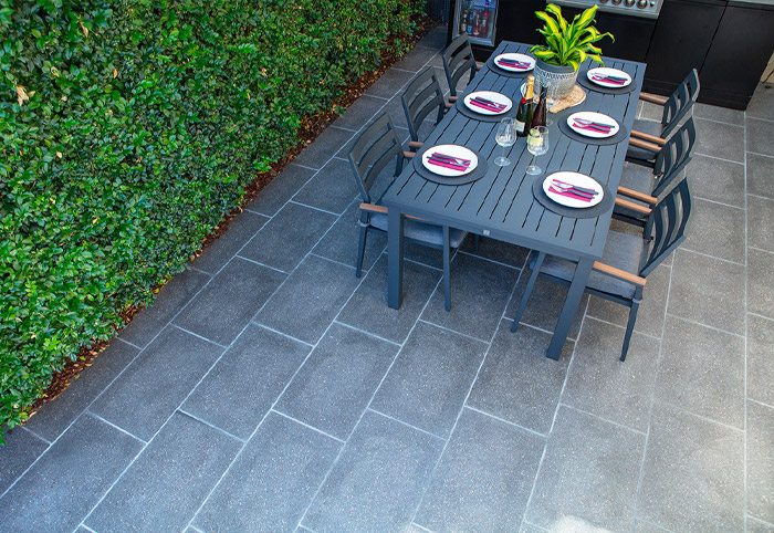 Overhead view of a courtyard with concrete paving and a black dining table.