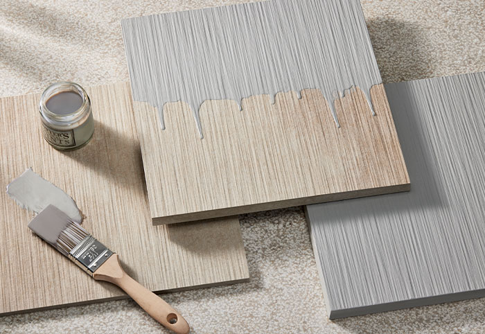 Half-painted samples of concrete cladding shown with a paintbrush and pot.