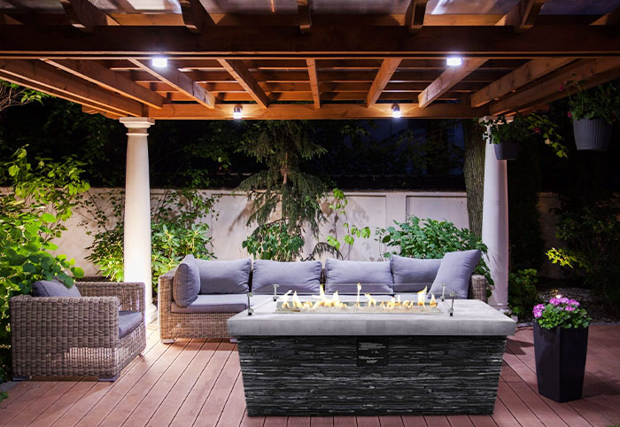 Island fireplace in an outdoor gazebo with sofas around it.