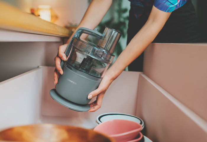 Compact food processor being placed into a kitchen drawer.