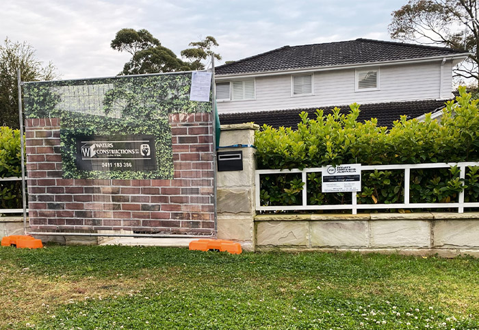 Rear fence of a house with a builder's sign displayed. 