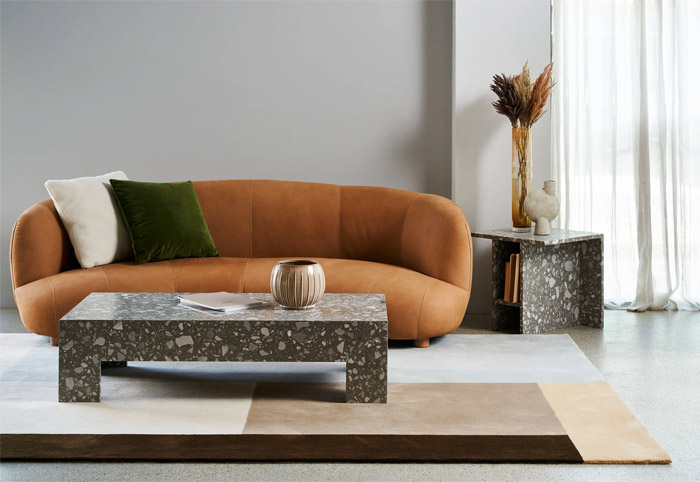 Living room with a tan couch and marble coffee table.