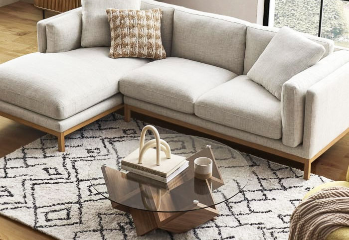 Circular glass coffee table next to a chaise sofa.