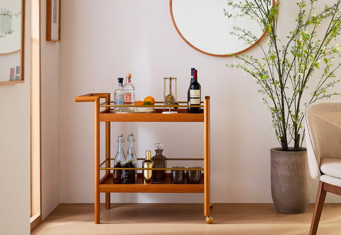 Brown wooden bar cart stocked with drinks.