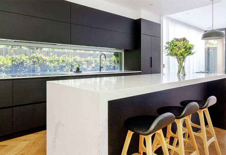 White bench in a black kitchen.