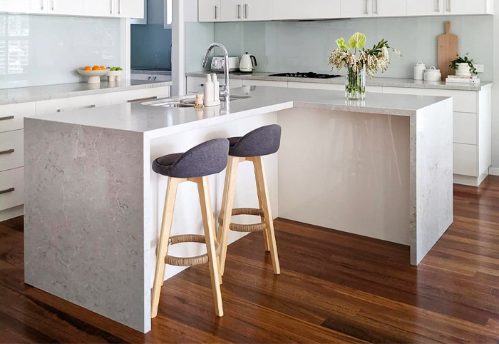 Corner kitchen bench with waterfall benchtop in a white kitchen.