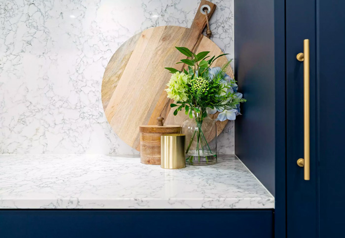 Close-up of a white stone splashback with blue kitchen cabinets.