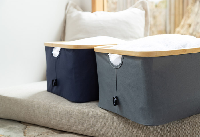 Two bamboo laundry baskets on a grey sofa.