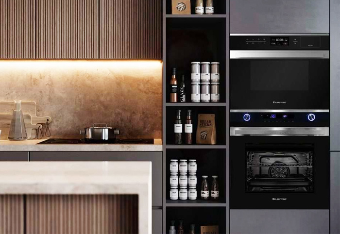 Black ovens built into dark kitchen cabinets. 