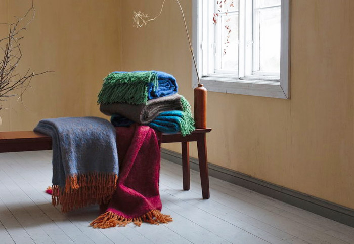 Designer mohair blankets on a wooden bench seat next to a window.