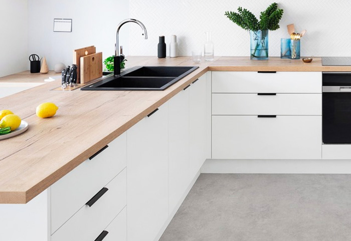 Scandi-style kitchen with wooden bench and black handles.