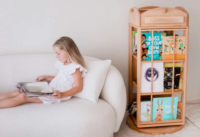 Girl reading on a sofa next to a bookcase.