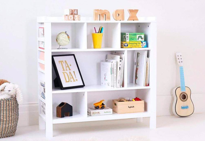 Kids' white bookshelf stocked with toys and books.