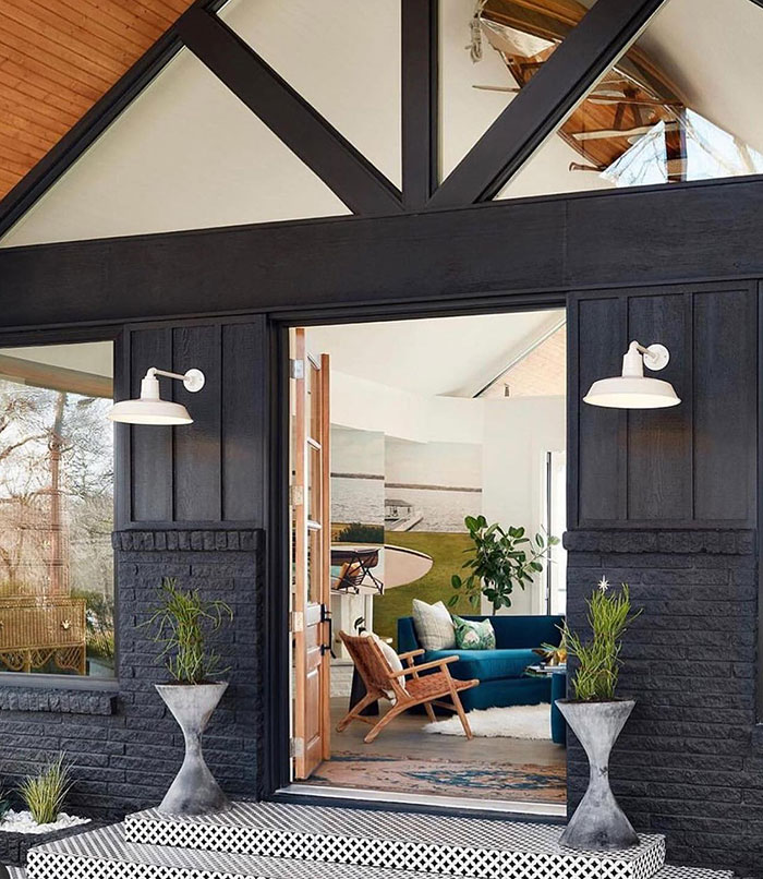 Entrance of a modern country home with white barn lights on either side of the doorway.