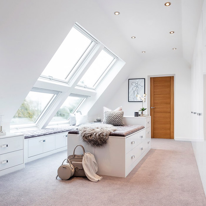 A loft that has been converted into a walk-in wardrobe with angled windows.