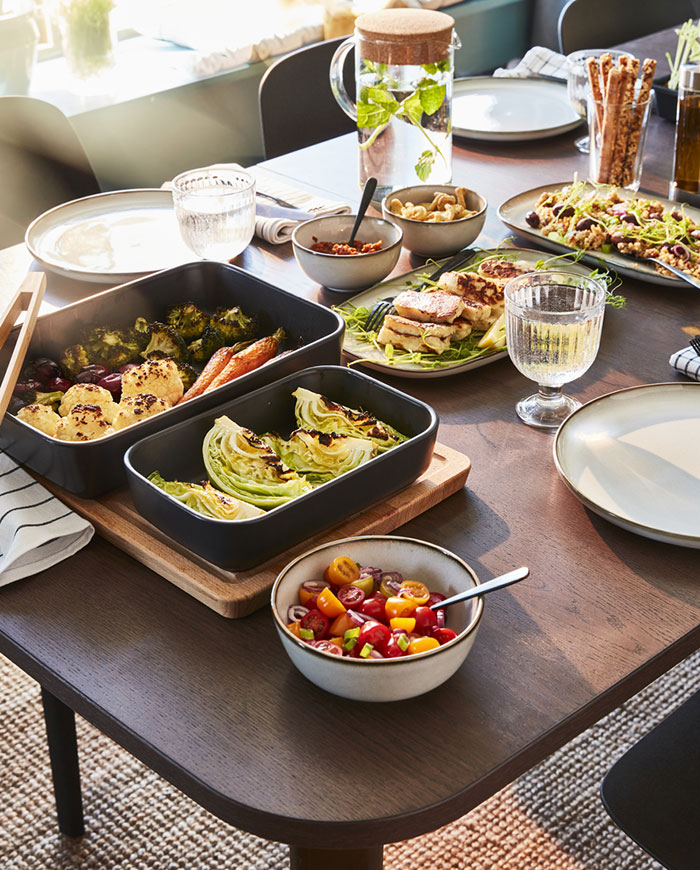 Wooden IKEA dining table filled with food and tableware. 