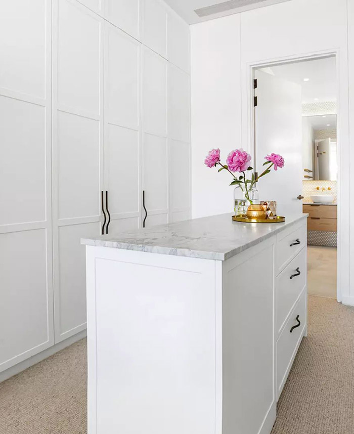 White walk-in robe with stone-topped cabinet at the centre. 