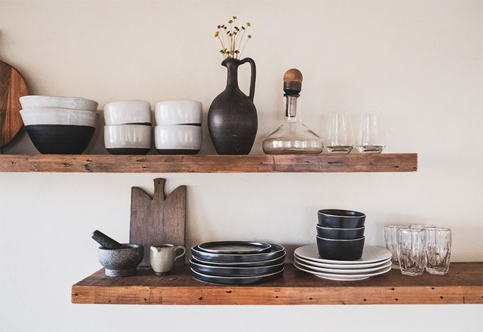 Two open timber shelves with tableware stacked on top.