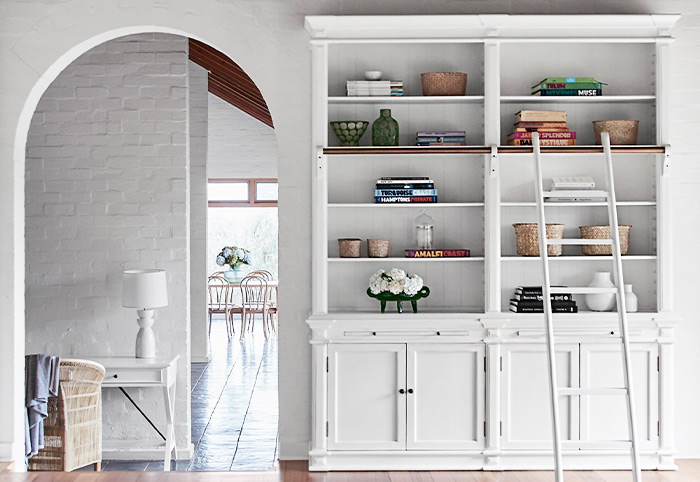 An open bookcase with a ladder positioned against a wall.