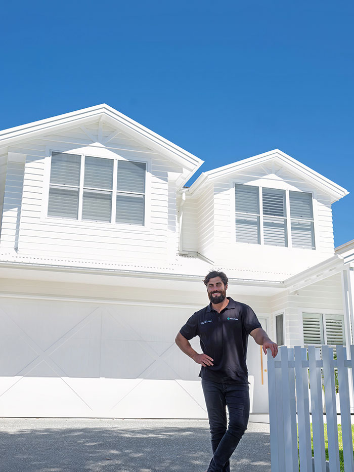 Neil Hipwell stands outside white Richmount house in Sydney.