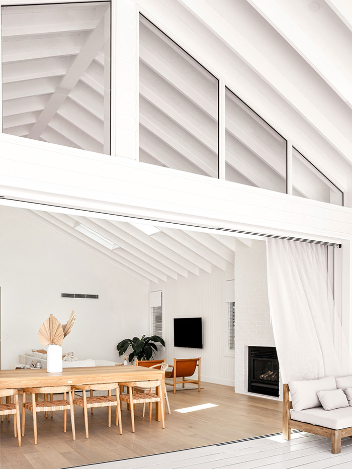 Looking inside from the deck of a white, modern beach house.