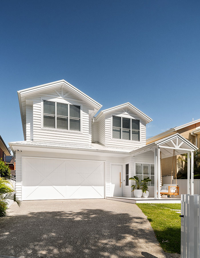 View of the front of a white two-storey weatherboard house from the driveway.