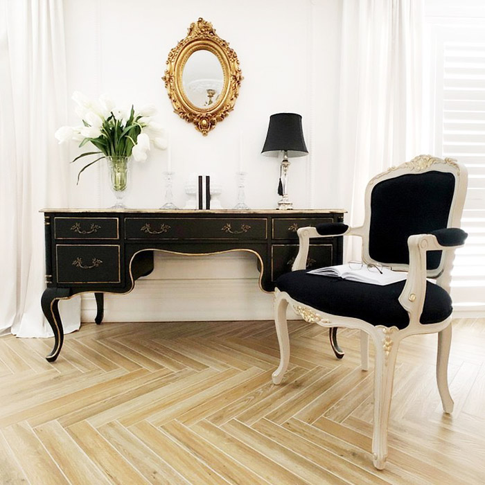 A Rustic black writing desk decorated with lamp and candle holder.