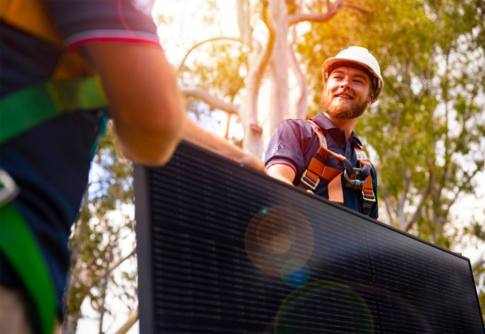 Men carrying solar panels for installation.