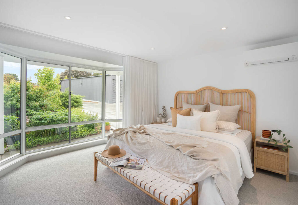 Bedroom with rattan bedhead and large bay window.