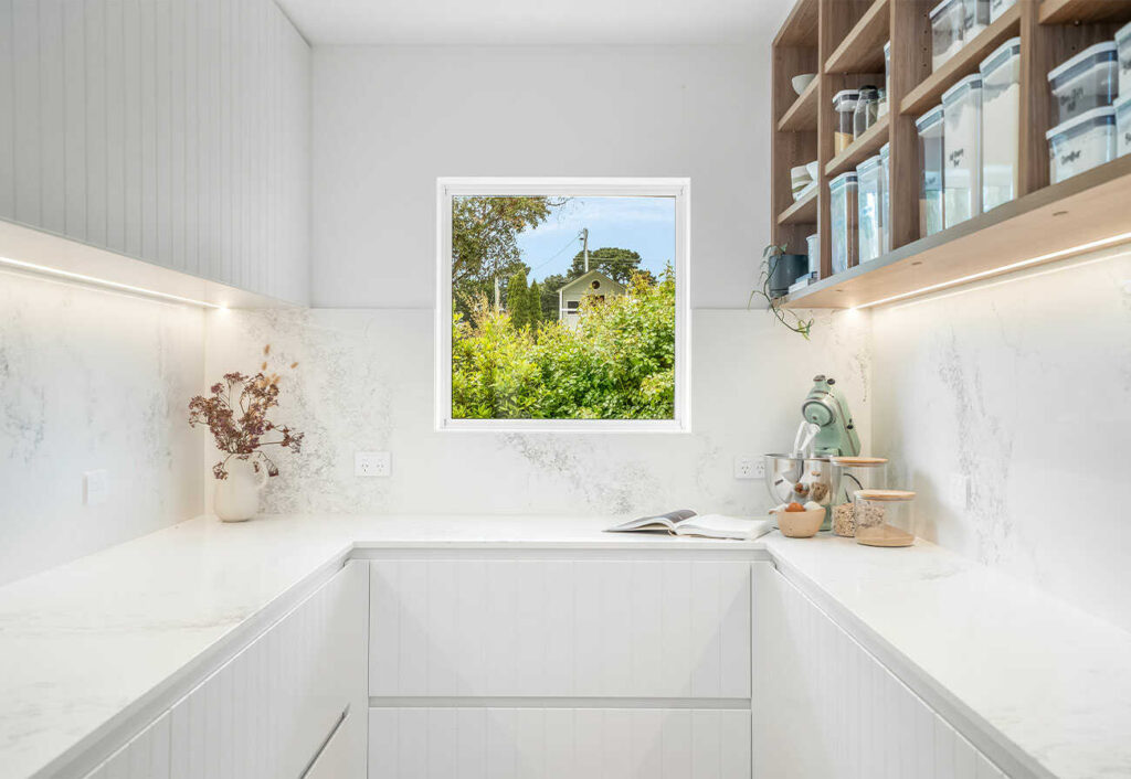 Butler's pantry with square window at one end overlooking a garden setting.