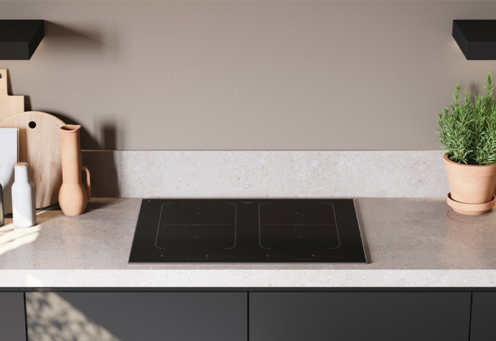 Black induction stove installed on a stone benchtop.