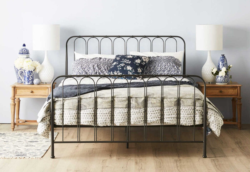 Timber bedside tables either side of a metal-framed bed.