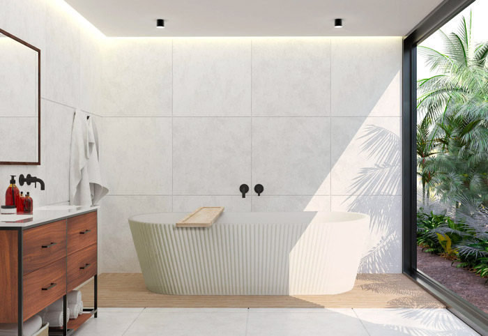 Ripple-edge freestanding bath next to a huge window overlooking a tropical garden.