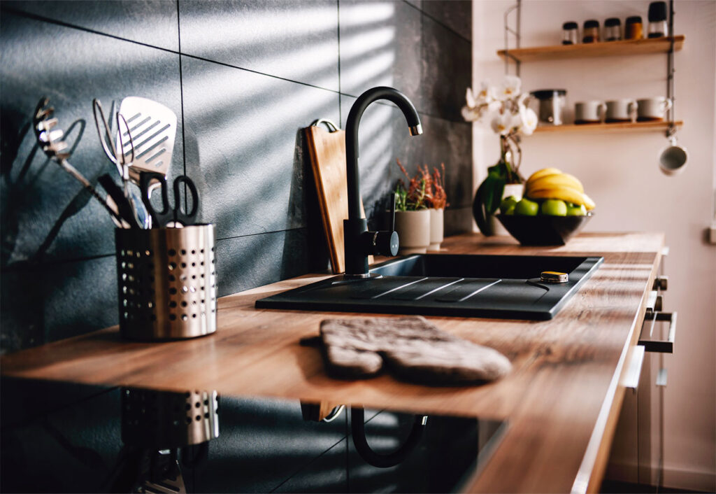 A black sink installed on a wooden benchtop.