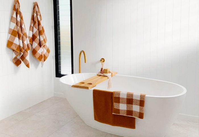 White bathroom with oval tub and gold tapware. 