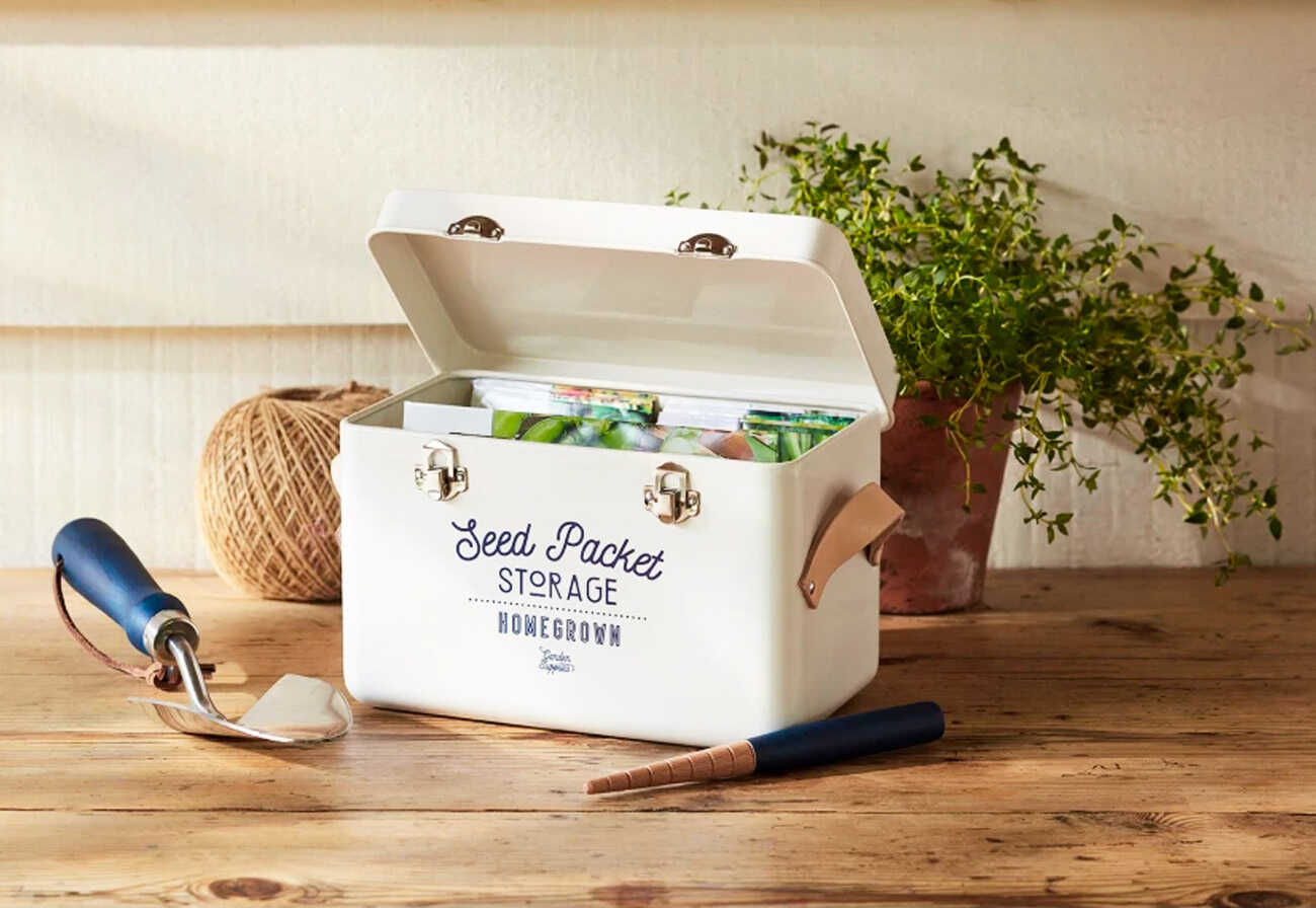 White seed packet storage tin on a wooden bench.