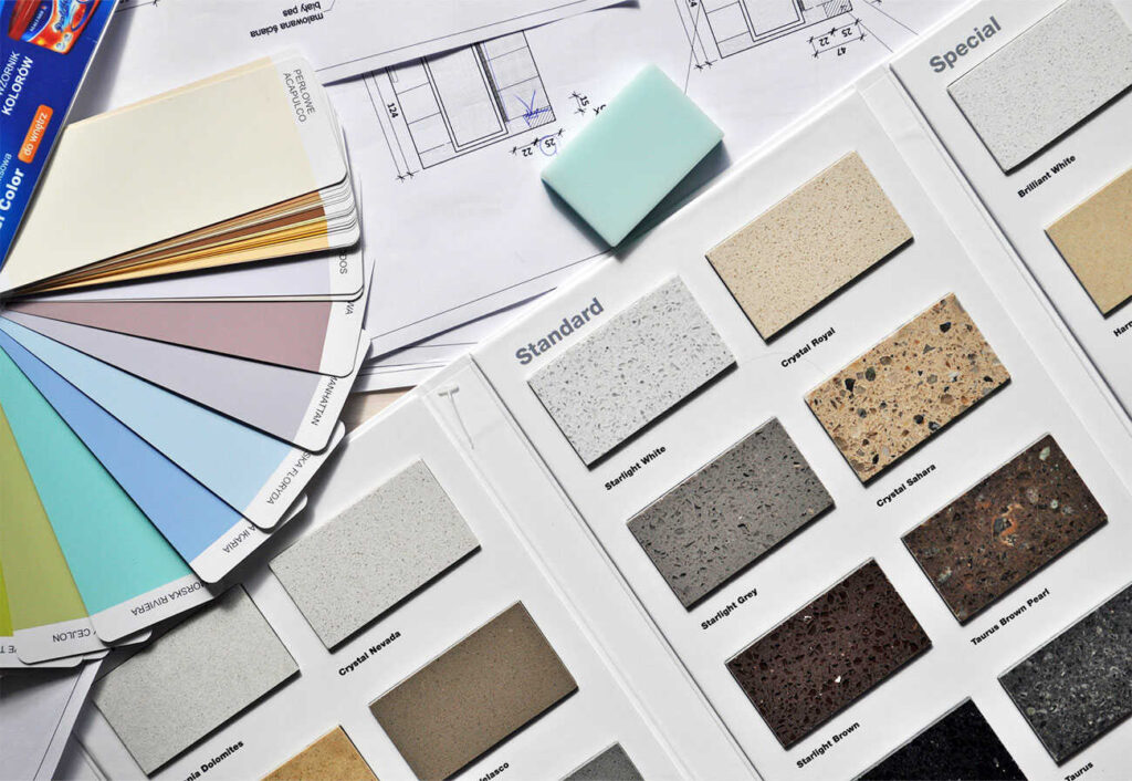 Paint swatches and tile swatches spread out on a table with house plans.