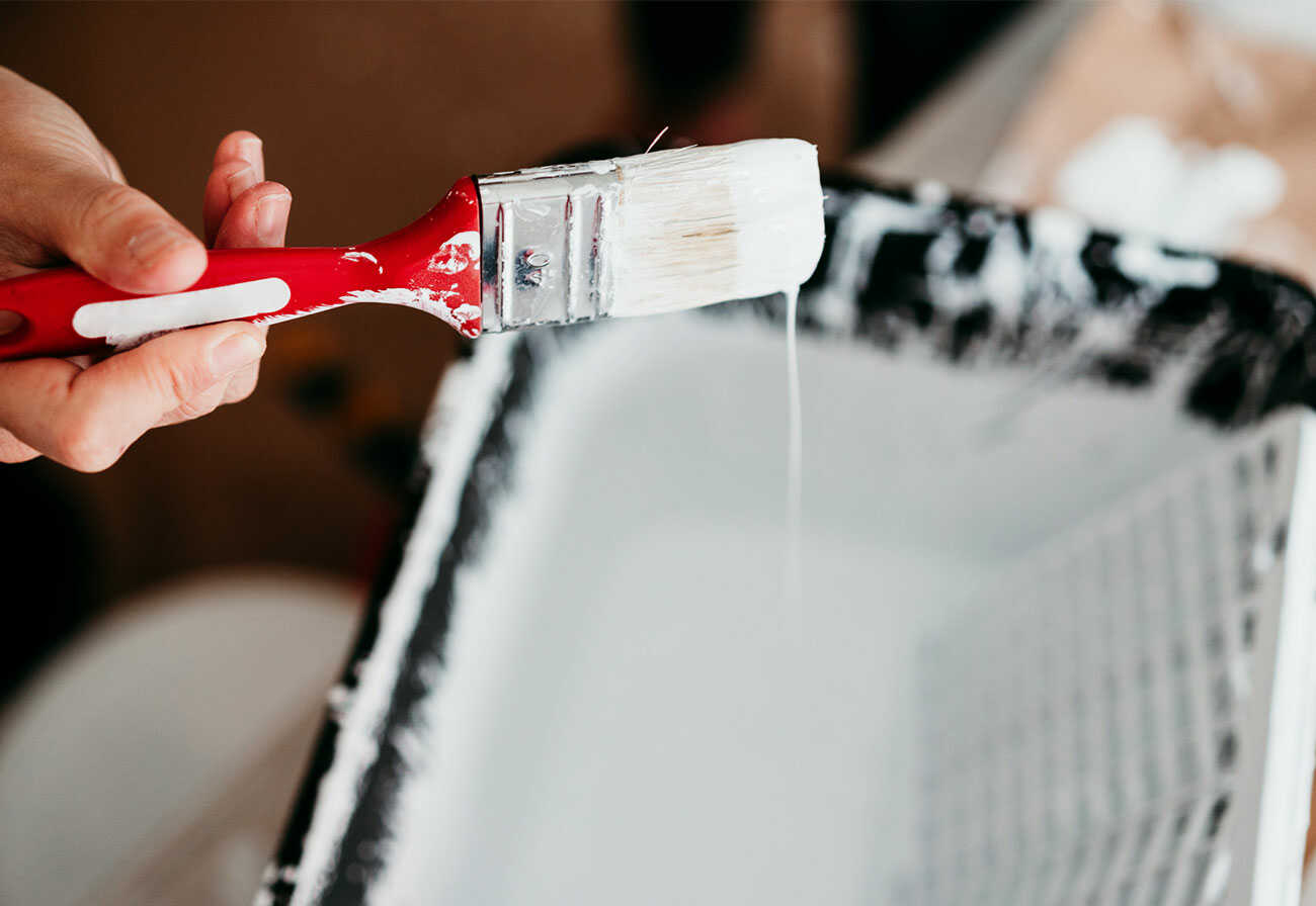 Paint brush and tray filled with white paint.