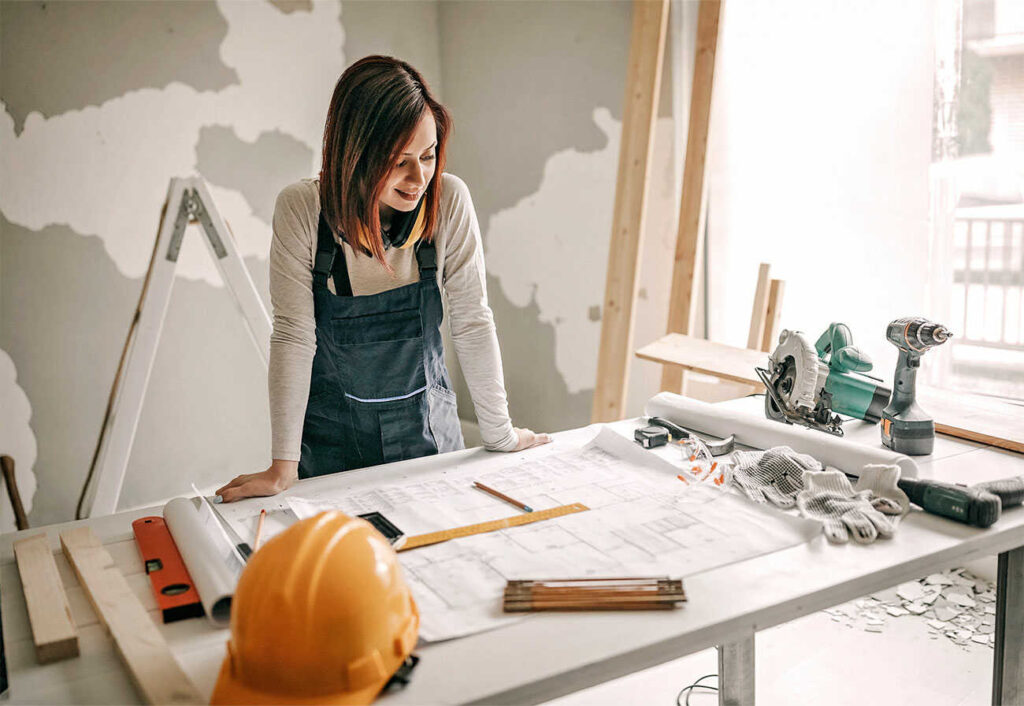 A women on a building site looking at house plans at a table.