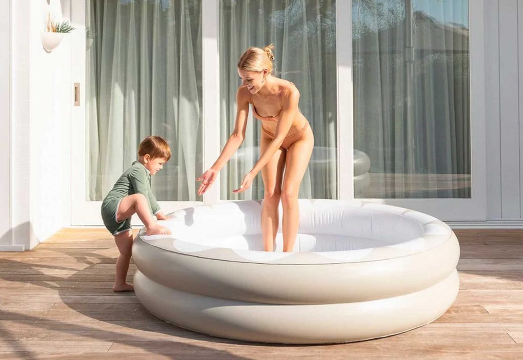 Mother playing in a stylish paddling pool on the deck with her child.