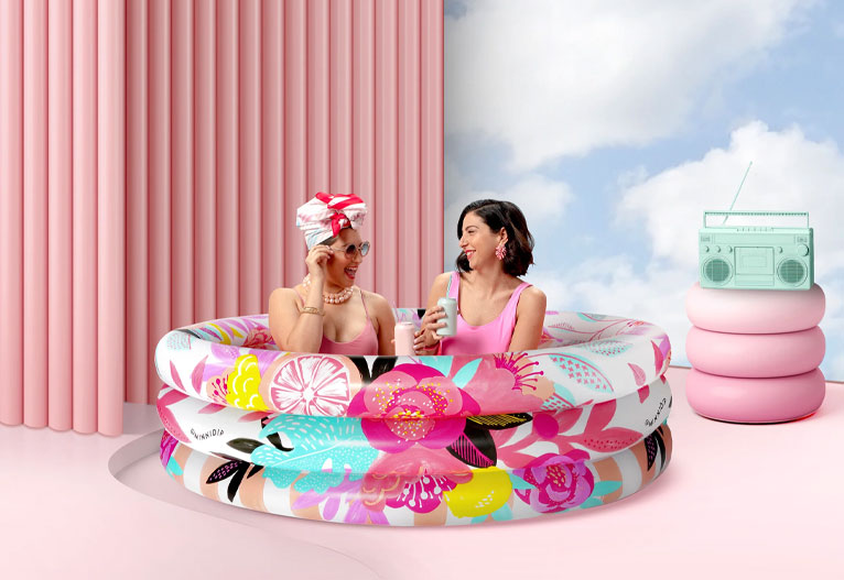 Glamorous women lounge in a designer paddling pool.